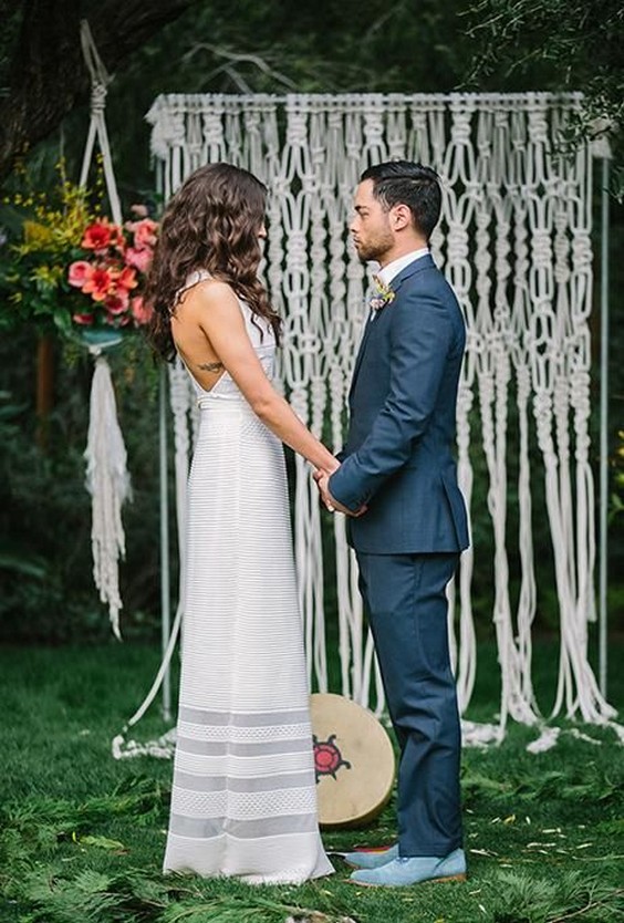 bohemian ceremony altar with a floor-grazing macrame backdrop and hanging potted flower arrangements