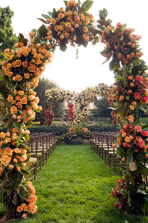 An arbor of pink and orange roses and a variety of greenery