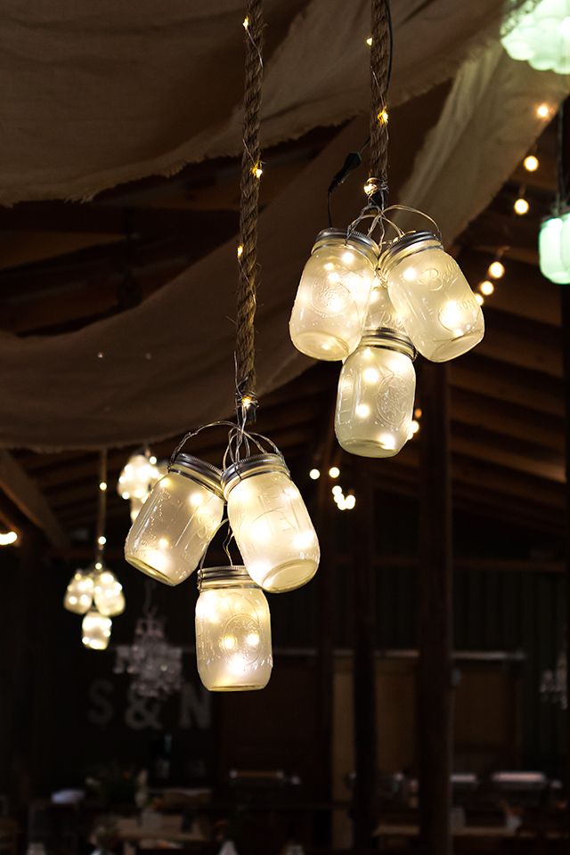 Clusters of frosted LED mason jar lights hung from the ceiling at this rustic barn wedding