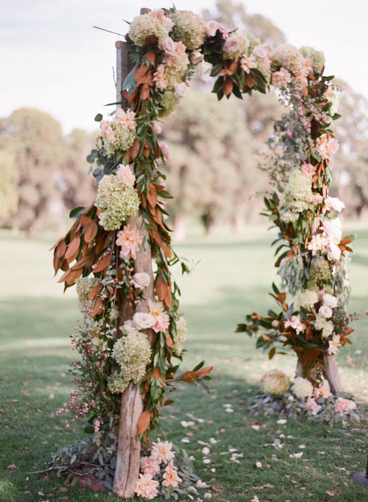 Fall florals decorating ceremony arch for rustic fall weddings