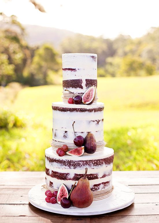 Red velvet wedding cake decorated with fresh fruit including Autumn plums cherries grapes and fresh figs