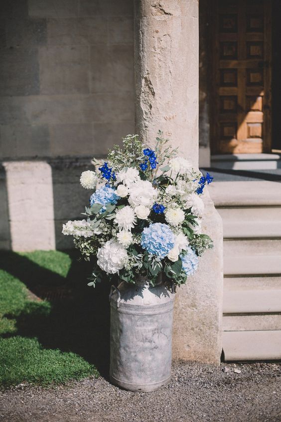 White and blue flowers in a rustic milk churn