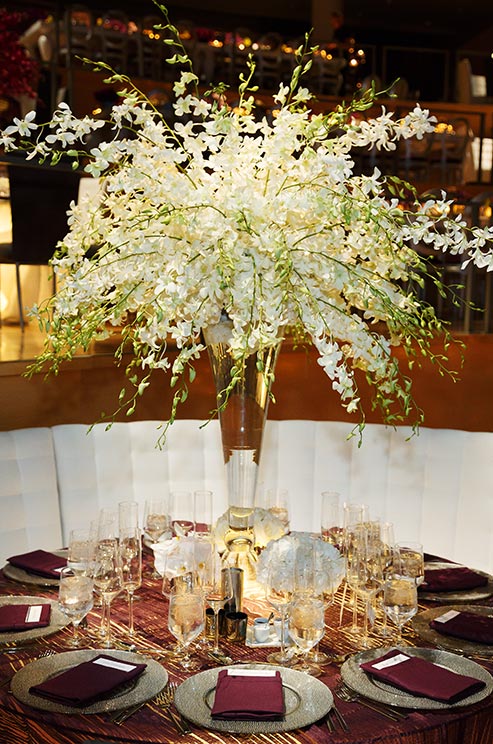 White dendrobium orchids juxtapose deep purple linens, creating a