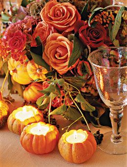 accent centerpieces that include autumnal-hued roses hydrangeas and scabiosa pods with some miniature pumpkin pear and apple votives