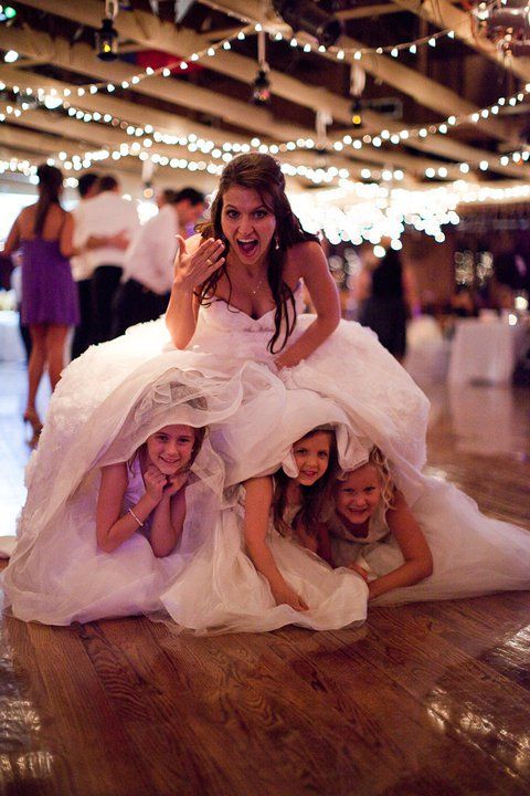 adorable flower girls hiding under dress unique wedding day photo ideas bride with flower girls wedding party blog