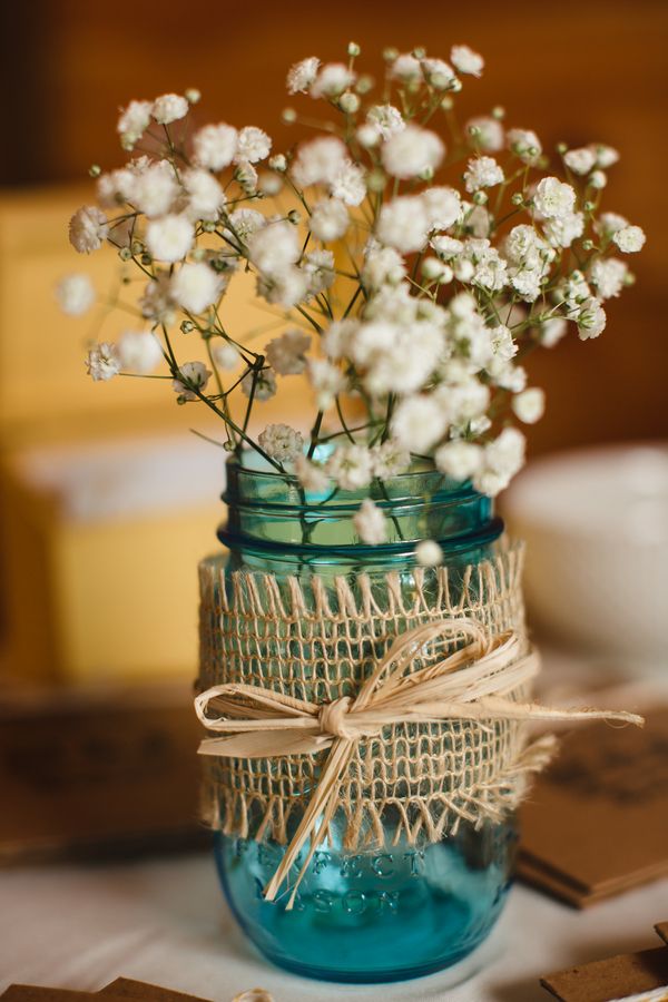 blue mason jars filled with baby's breath and wrapped with burlap