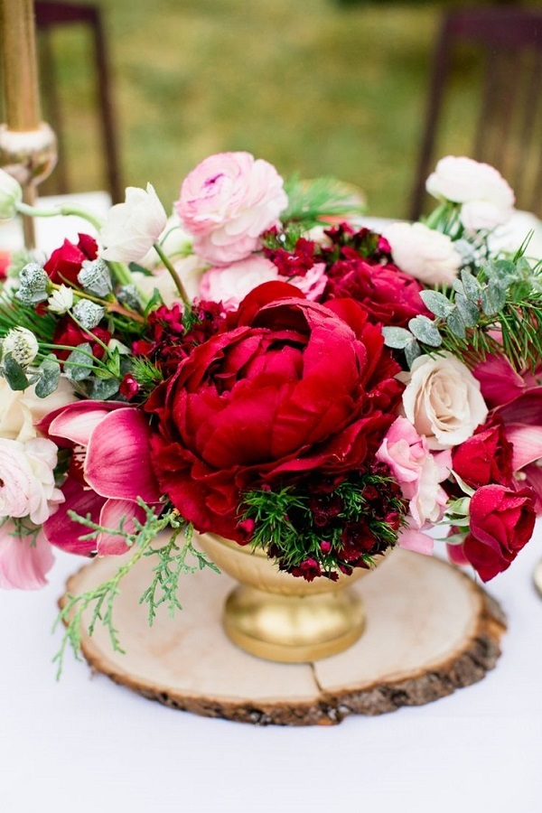 cranberry Peony arrangement on a rustic wood round