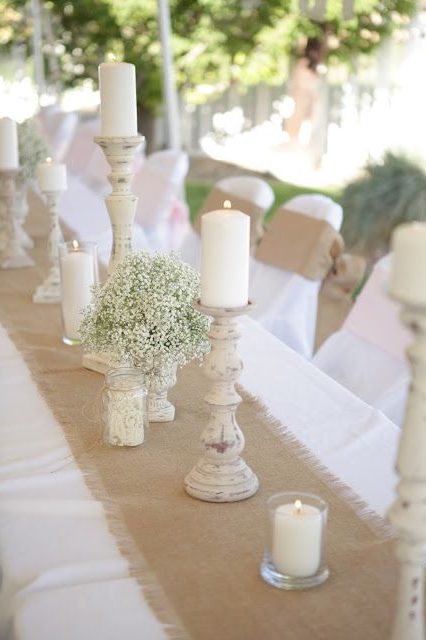 create drama with a burlap runner over a simple white table cloths and rustic candle holder centerpieces