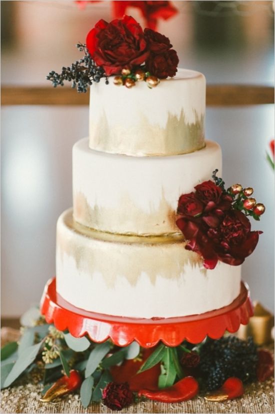 gold and red wedding cake with floral accessories