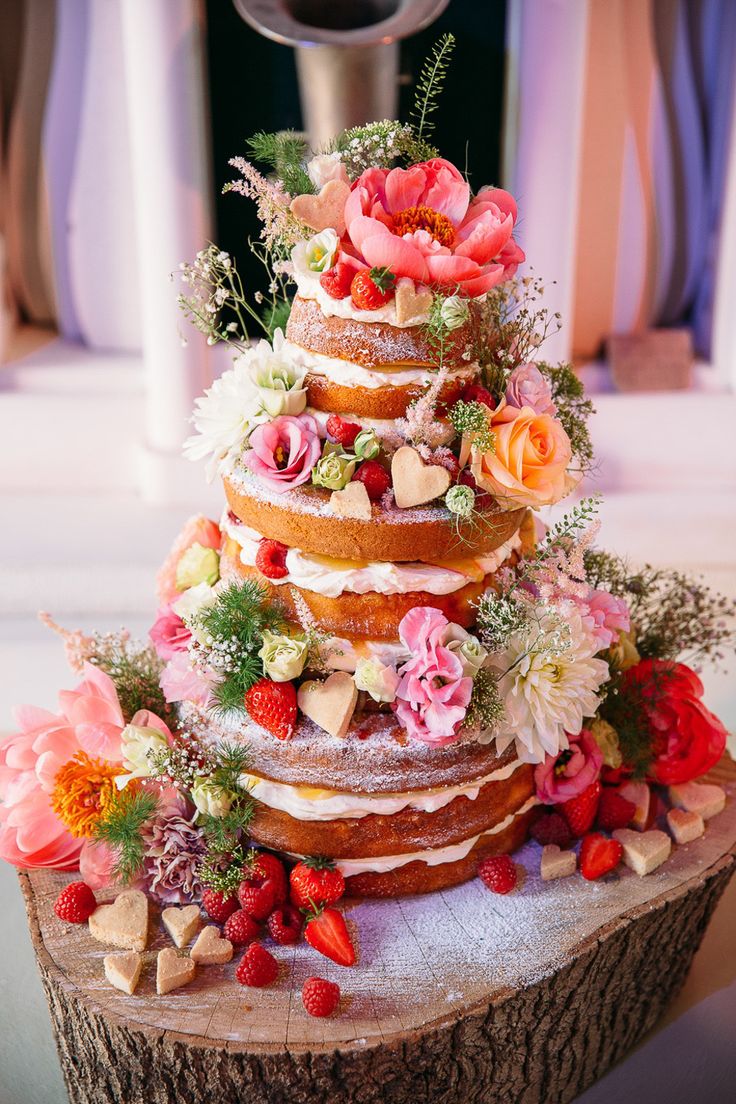 naked wedding cake filled with strawberries, raspberries and fresh cream, decorated with shortbread hearts and flowers
