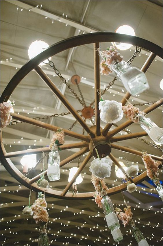 vintage wood wheel chandelier with hanging bottles and flowers
