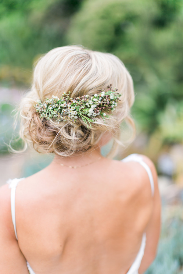 A fresh spray of tiny pink blossoms completes the natural vibe of this messy updo
