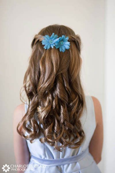 Flower girl with blue flowers in her half-up hairstyle Flower girl with blue flowers in her half-up hairstyle