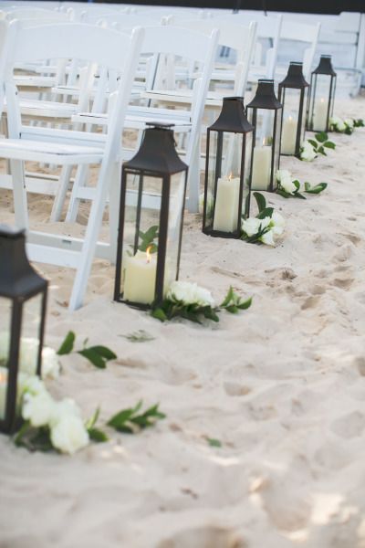 Lanterns and flowers line the beach aisle