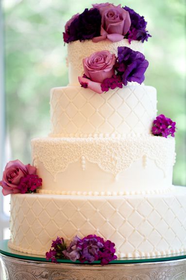 White lace wedding cake with pink and purple flowers