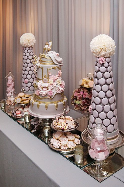 dessert table features two purple macaron pyramids topped with pomanders of cupcake liners
