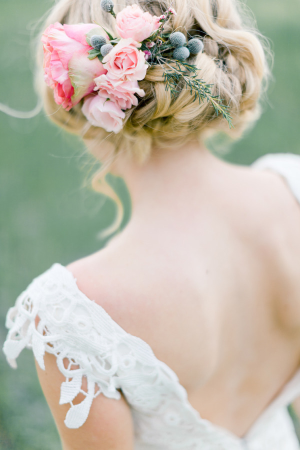 messy low bun updo hairstyle with blush pink flowers