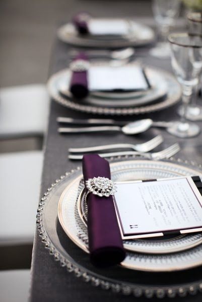 wedding table top with purple napkins in napkin ring with menu and china on grey linen