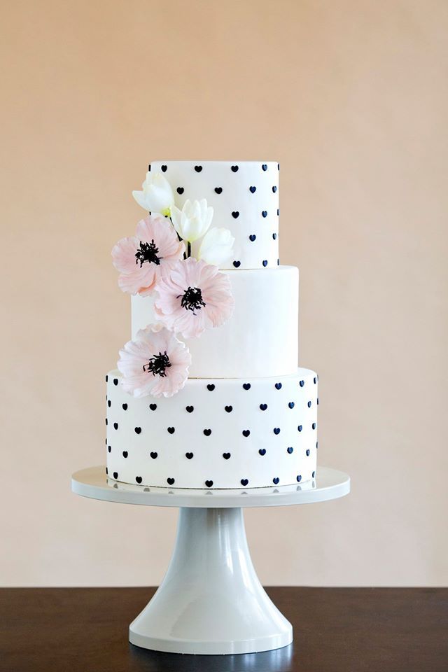 white and balck wedding cake wth pink flowers and smail heart details