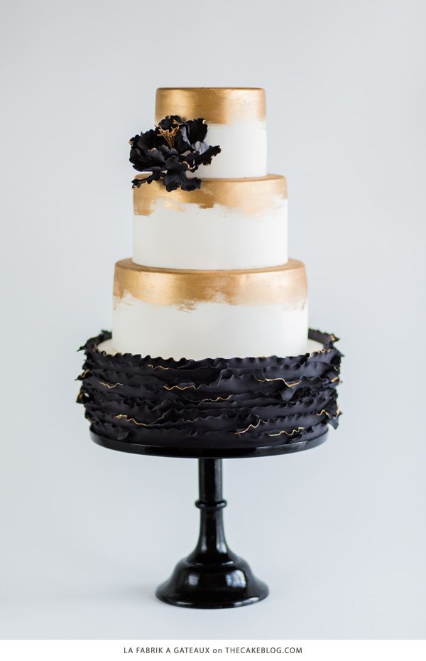 white and gold wedding cake with black ruffles