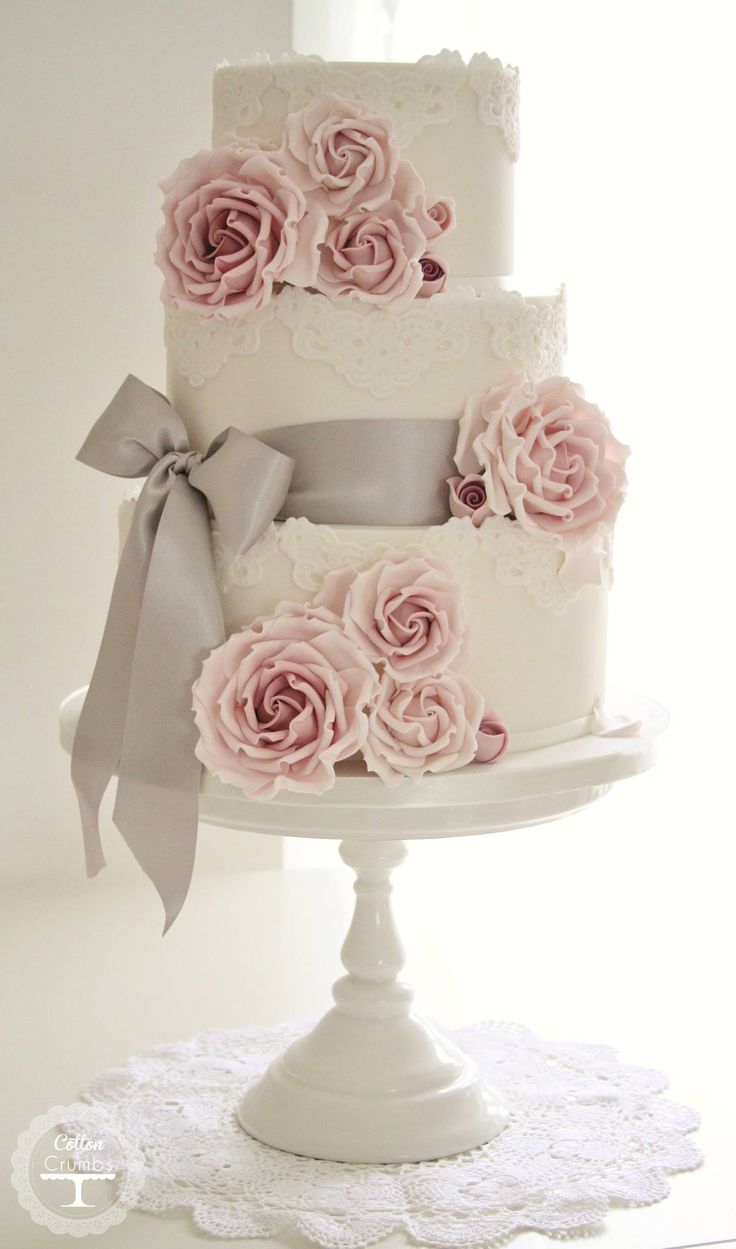 white lace wedding cake with pink roses and gray ribbon