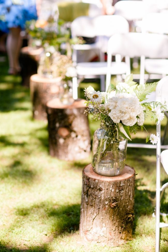 wildflowers in mason jar on tree stump woodland wedding aisle