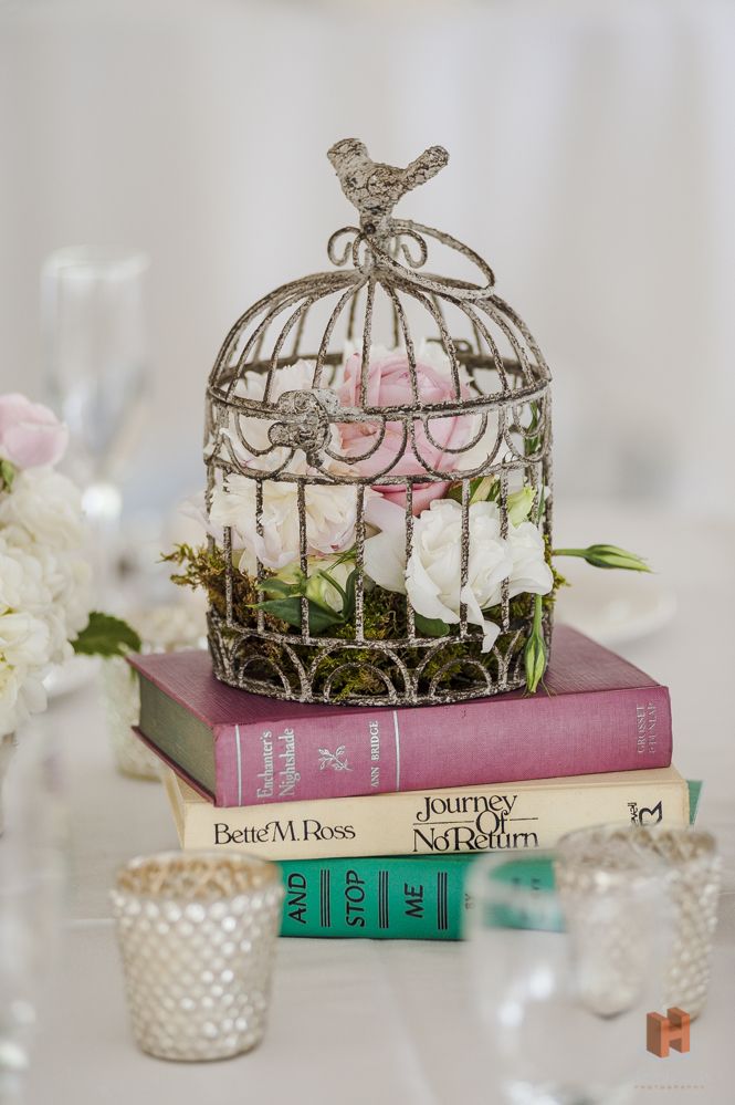 flowers in birdcage on books wedding center piece for vinatge weddings