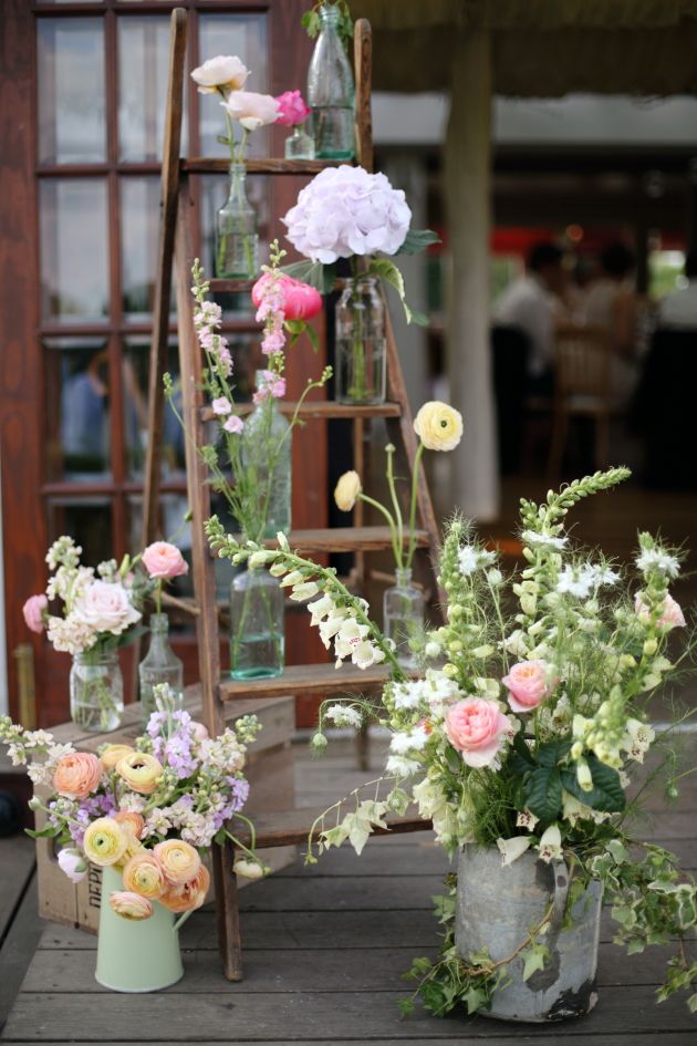rustic wedding decor ladder decorated with flowers in jars and watering cans