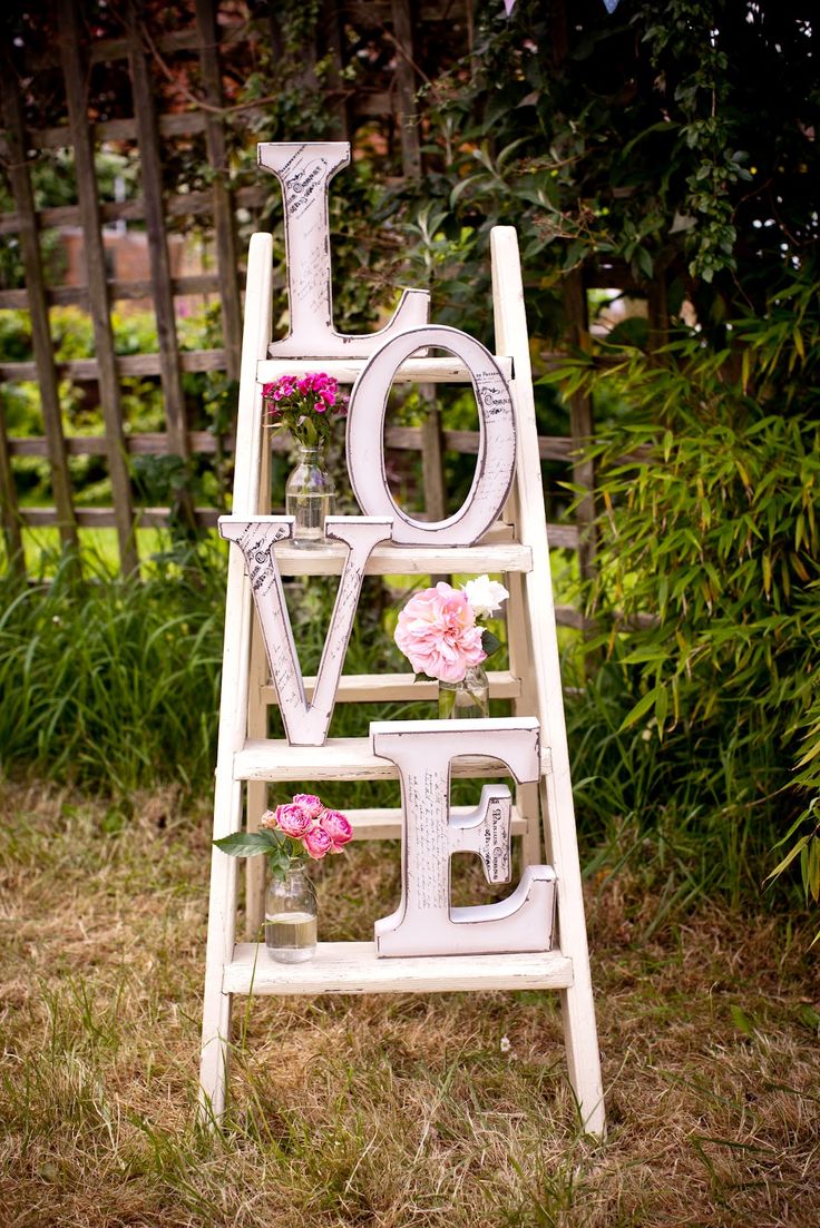 vintage white display piece made with white ladder, pink flowers, clear jars, and huge letters