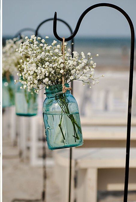 Antique blue mason jars with baby's breath on shepherd hooks along aisle