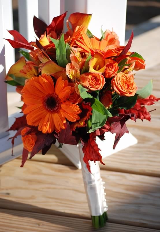 Orange gerbera, mango spray roses, mango calla lilies, orange alstromeria and fall leaves wrapped in white satin with pearls