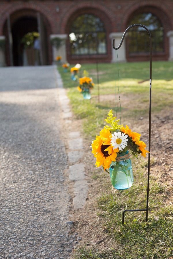 sidewalk at Avondale Villa was lined with blue mason jars on shepherd hooks filled with sunflowers, daisies, and solidago