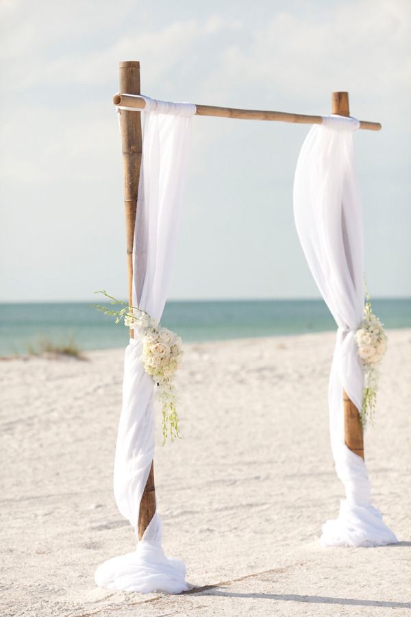 simple bamboo white wedding arch on the beach