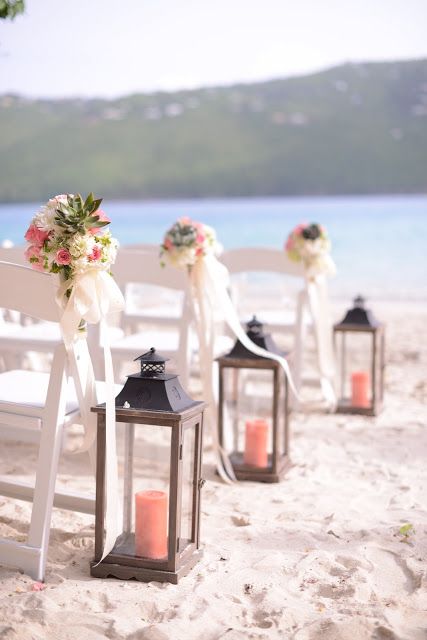 wooden lanterns with coral pillar candles lining the aisle