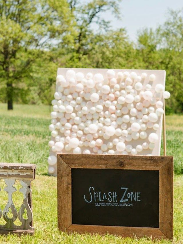 Guests throw darts at balloons filled with paint attached to a canvas