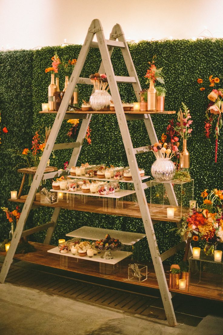 Miniature desserts displayed on a step ladder with faux hedge backdrop