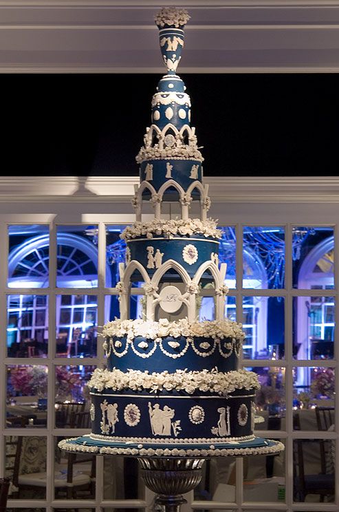 five-tiered wedding cake is decorated in blue and white, with columns, flowers and white fondant vignettes