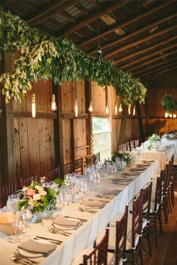 Hanging lights and long tables gussy up a barn reception
