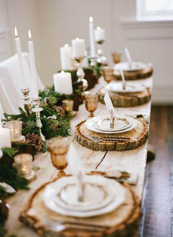 Rustic winter wedding table setting with candles, fresh greens and pinecones