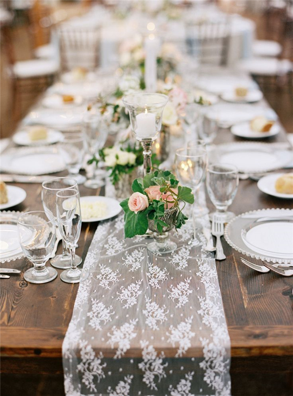 25 Chic Country Rustic Wedding Tablescapes 11 lace table runner over a rustic wooden table at a wedding reception or dinner party