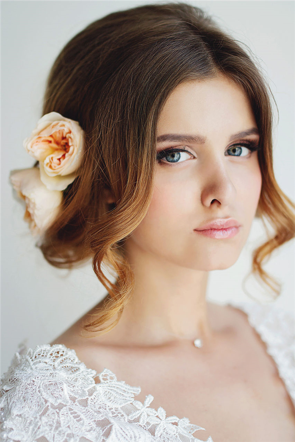 messy wedding updo with coral flower