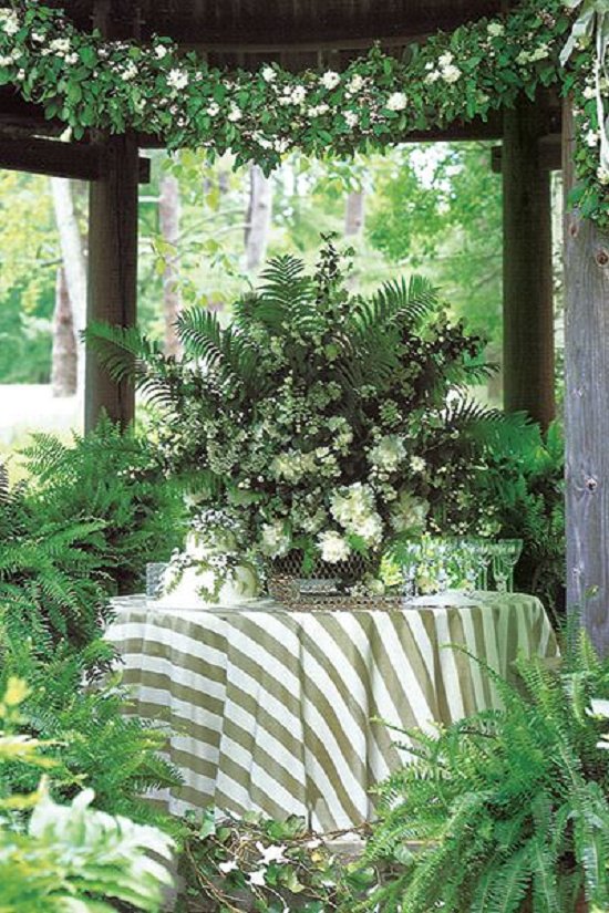 Adelicate cake nestled beneath a centerpiece of ferns, miniature roses and peonies