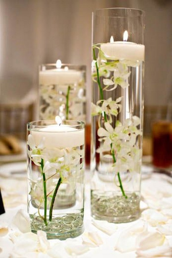 Varying glass cylinders filled with floating candles and submerged flowers