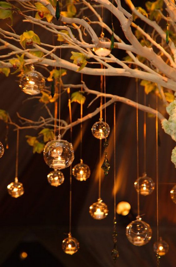 Glass bubbles hold tealight candles and gracefully descend from limbs of a tree