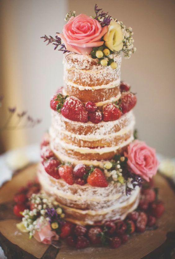 Tall naked wedding cake decorated with roses and strawberries