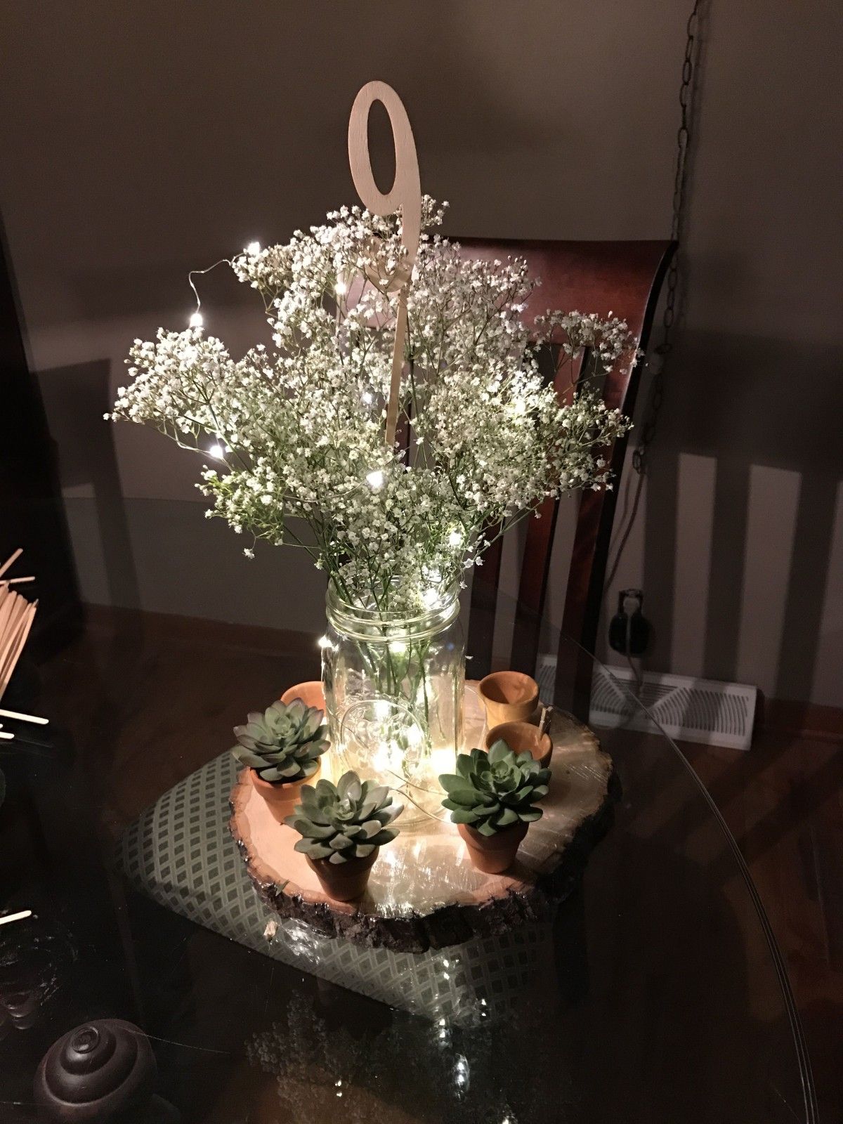 Baby's breath mason jar with fairy lights and succulents in tiny pots on tree slice disk centerpiece