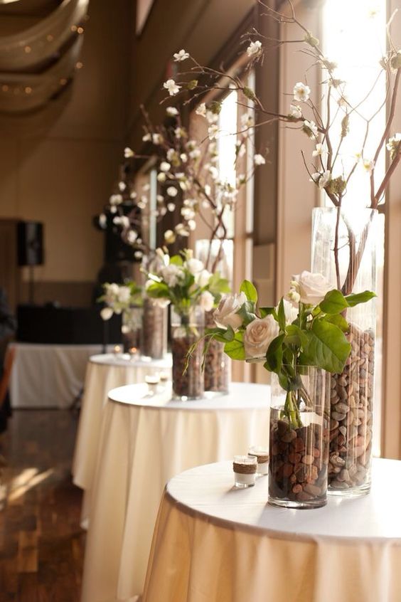 Cylinders with river rock roses and branches wedding centerpiece