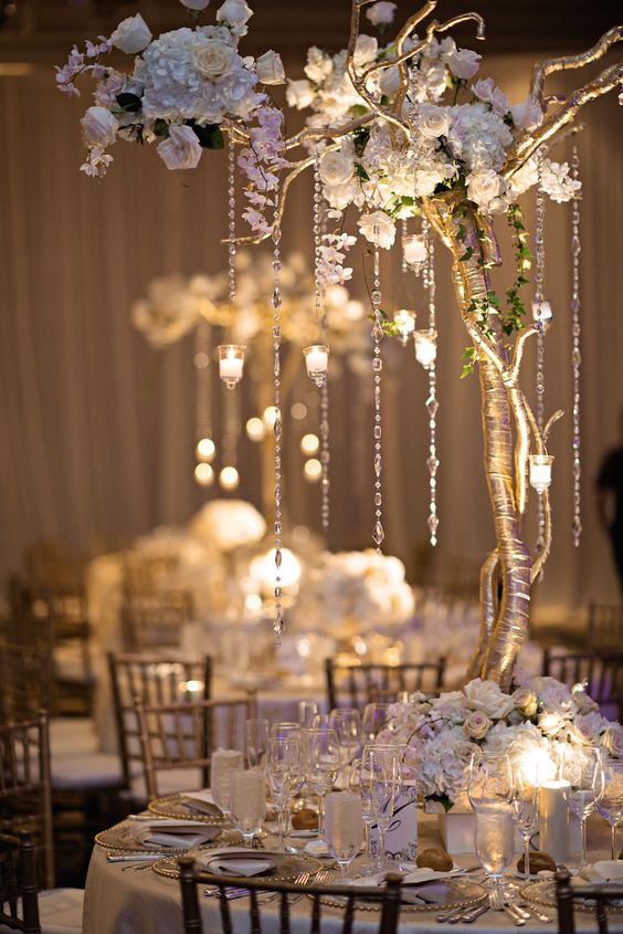 Guest tables were decorated with gilt-wrapped trees and florals, cascading crystals