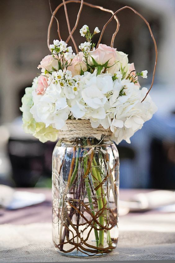 large jar filled with fresh flowers, branches and wrapped with rope reception wedding flowers