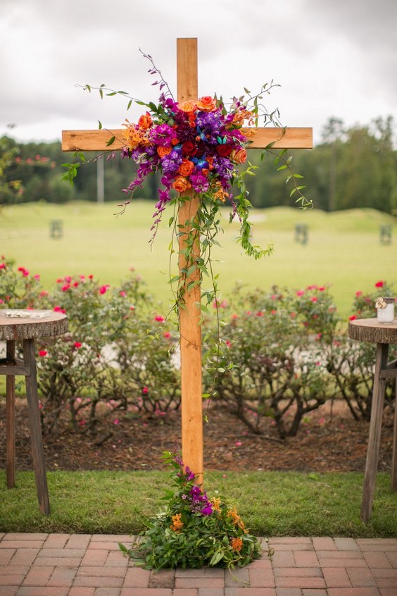 orange and purple flowers adorned cross wedding arch